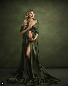 a pregnant woman in a green gown posing for the camera with her belly exposed and long legs