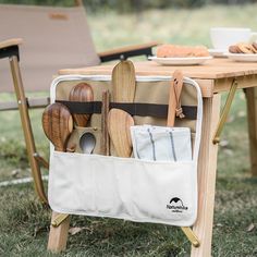 an outdoor picnic table with utensils and wooden spoons in the back pocket