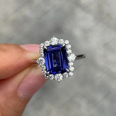 a woman's hand holding an engagement ring with a blue sapphire and white diamonds