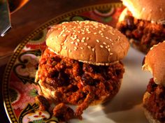 three sloppy joes on a plate with a knife