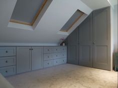 an attic bedroom with gray cabinets and white carpeted flooring on top of the walls