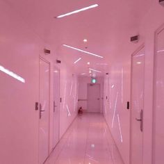 a long hallway with white walls and doors leading to another room on the other side