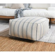 a living room with a white couch and footstool on the rug in front of it