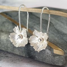 A pretty pair of silver drop flower earrings. These floral dangle earrings are an ideal gift for her at birthdays, Mothers day or anniversaries.  They also make for perfect wedding jewellery for brides or as bridesmaid gifts. Handmade from recycled sterling silver. Inspired by nature I have included matching studs, necklace and bracelet available with the same design. Each flower is individually cut by hand before adding the petal texture. Comfortable hand made ear wires are added before the dan Feminine Earrings, Wedding Jewelry For Bride, Handmade Silver Jewellery, Flower Drop Earrings, Silver Flower Earrings, Sterling Silver Drop Earrings, Sterling Silver Flowers, Floral Jewellery, Delicate Earrings