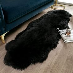 a long black sheepskin rug on the floor next to a blue couch and coffee table