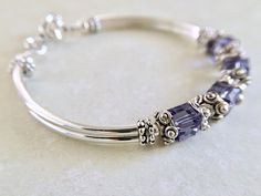 This comfortable bangle bracelet is so pretty in person. Perfect for your bridesmaids on your special wedding day! Can also be given for an anniversary, birthday or mothers day gift among many others... Choose from many colors from the dropdown menu at checkout. ~ 6mm tanzanite swarovski crystal cubes ~ pewter bead caps ~ silver plated tube bead bangles and toggle Click here to return to my shop's homepage: https://www.etsy.com/shop/beadedjewelryforyou?ref=simple-shop-header-name&listing_id= Adjustable Stackable Crystal Bracelet For Wedding, Adjustable Stackable Crystal Wedding Bracelet, Purple Bangle Jewelry For Wedding, Purple Wedding Bracelet Jewelry, Adjustable Birthstone Beaded Bracelets For Anniversary, Adjustable Purple Bracelet For Anniversary, Adjustable Sterling Silver Crystal Bracelet For Anniversary, Silver Beaded Bracelets With Birthstone For Wedding, Adjustable Purple Bracelets For Anniversary