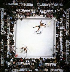 an aerial view of two men playing tennis in the middle of a room full of people