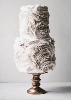 a three tiered cake sitting on top of a metal stand covered in white frosting