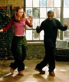 two people are dancing together in an old room with exposed brick walls and large windows