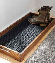 a pair of hiking boots sitting on top of a wooden floor mat next to a rug