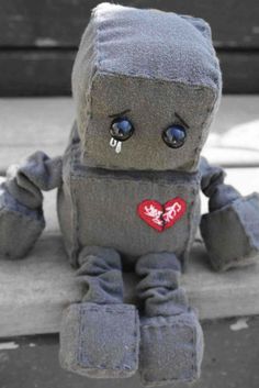 a small gray stuffed animal sitting on top of a bench