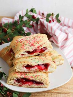 strawberry shortcakes with sprinkles on a white plate next to flowers