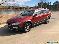 a red volvo suv parked in front of a lake