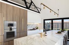 a modern kitchen with marble counter tops and stainless steel appliances in front of large windows