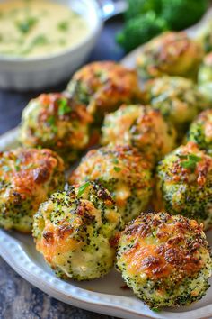 broccoli covered in cheese on a plate next to dipping sauces and dip