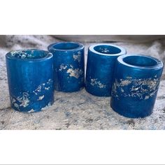 four blue glass vases sitting on top of a stone floor next to each other