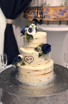 a three tiered wedding cake with blue flowers on top