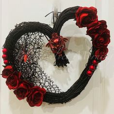 a heart shaped wreath with red roses on the front and side, attached to a white door