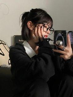 a woman sitting on a couch taking a selfie with her cell phone while wearing glasses