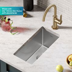 a stainless steel kitchen sink with faucet and soap dispenser next to it