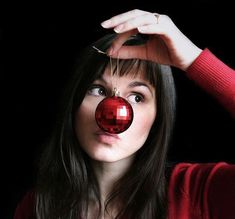 a woman holding a red ball in front of her face