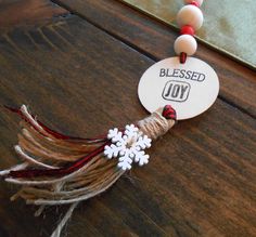 a wooden table topped with a snowflake and beaded necklace on it's cord