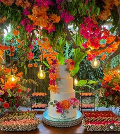 a wedding cake and desserts on a table in front of an array of flowers