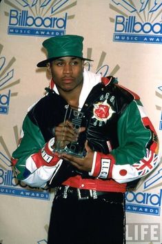 a man in a green hat and jacket holding an award for best rap album at the billboard music awards