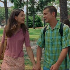 a young man and woman holding hands in the park