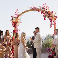 a bride and groom standing under an arch with flowers on it at their wedding ceremony