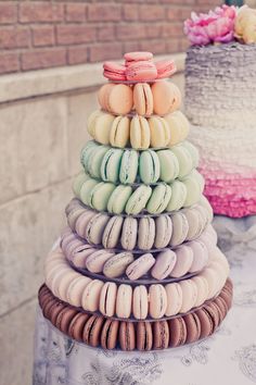 a stack of macaroons sitting on top of a table next to a cake