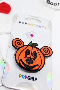 an orange and black mickey mouse pin sitting on top of a white card with the word popgrip