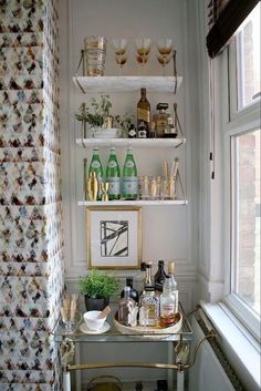 a bar cart in the corner of a room with bottles and glasses on top of it