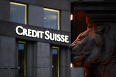 a building with a sign that reads credit suisse next to a statue of a lion