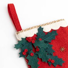 a christmas stocking with holly leaves and red berries hanging from it's side