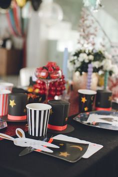 the table is set with black and white striped paper cups, plates, and utensils