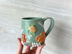 a hand holding a ceramic mug with sea animals on it