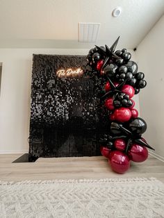 there is a black and red balloon sculpture on the floor in front of a wall