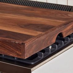 a wooden cutting board sitting on top of an oven