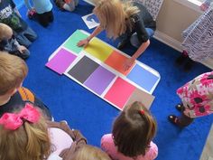 a group of children sitting on the floor playing with color samples