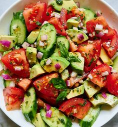 a white plate topped with cucumber and tomato salad