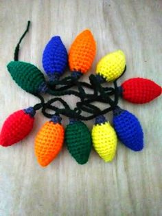 crocheted christmas lights on a table with black cord and white background, top view