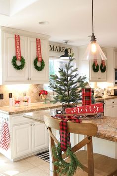 a kitchen decorated for christmas with wreaths on the counter and decorations hanging from the ceiling