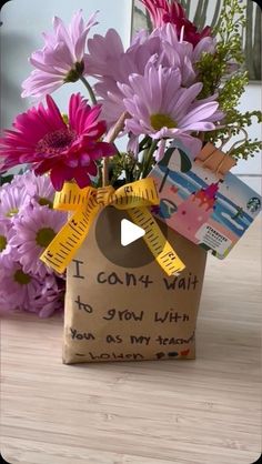 a vase filled with purple flowers on top of a wooden table next to a card board