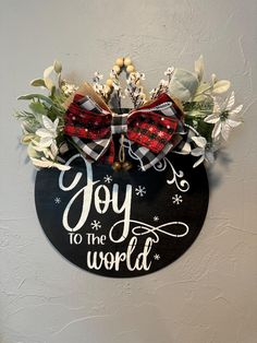 a sign that says joy to the world on it with bows and snowflakes