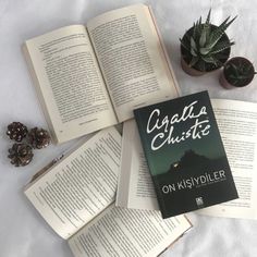 an open book sitting on top of a bed next to some plants and other items