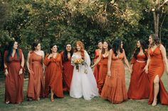 a group of women standing next to each other in front of some trees and bushes