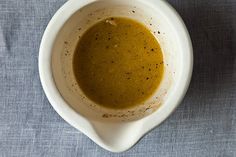 a white bowl filled with brown liquid on top of a blue cloth covered tablecloth