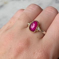 a woman's hand with a gold ring and a pink stone in the middle