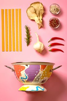 various ingredients are arranged on a pink background, including garlic, peppers, and onions